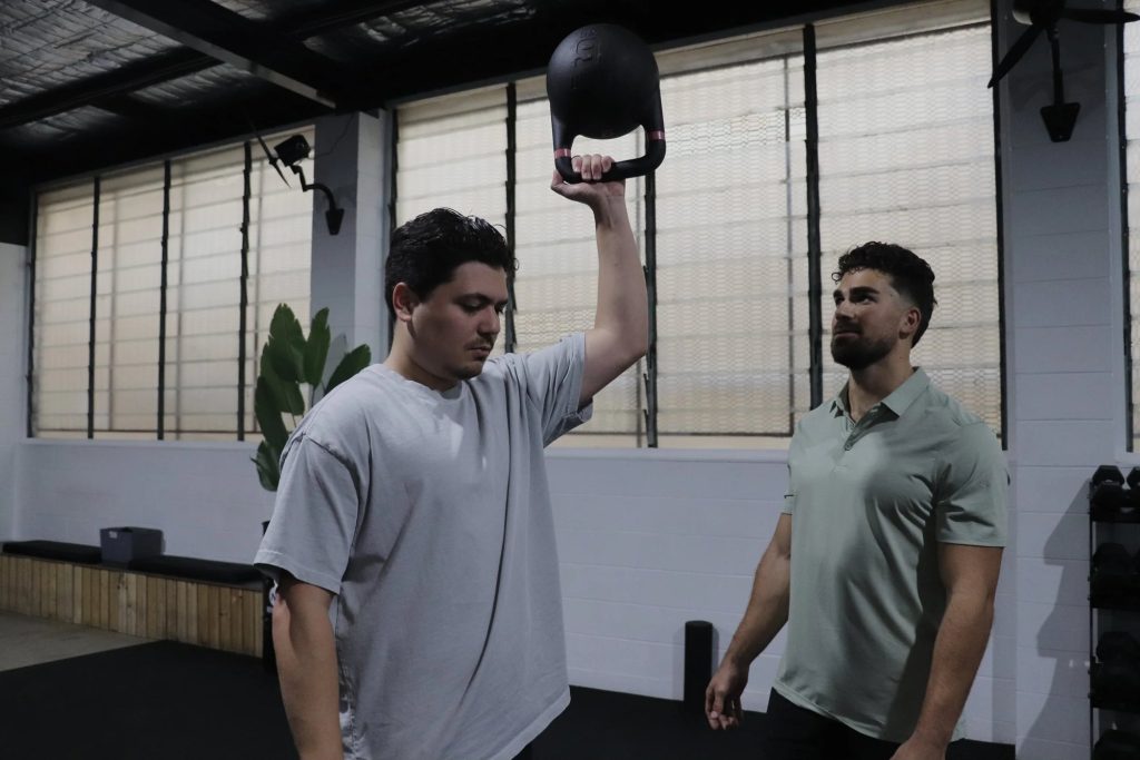 Ahrie coaching an overhead kettlebell press